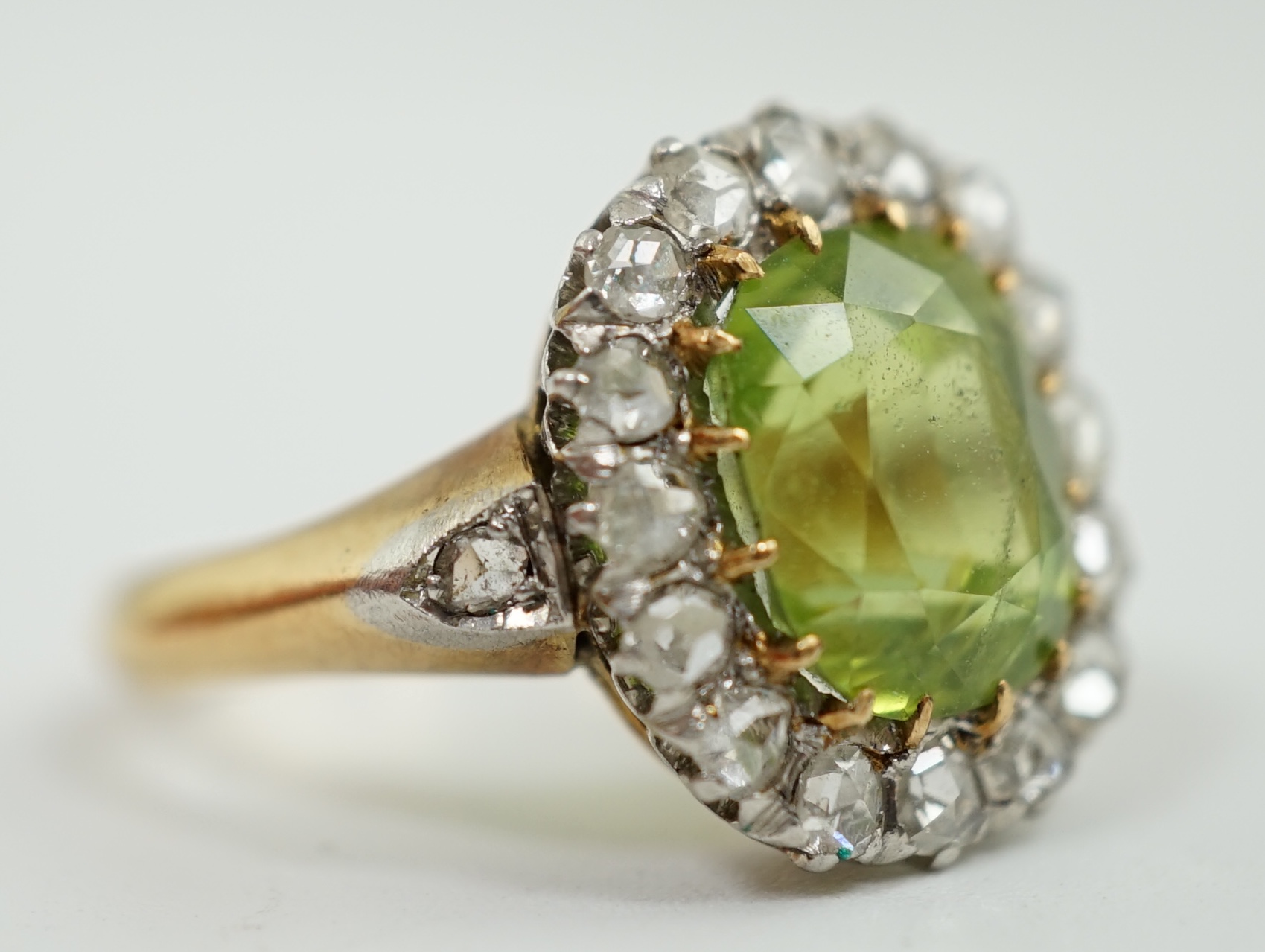 An early 20th century gold, peridot and diamond set oval cluster ring